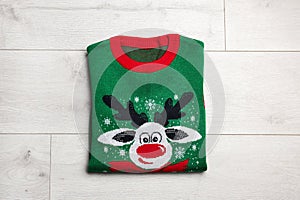 Folded warm Christmas sweater on wooden table, top view
