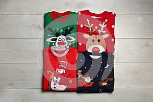 Folded warm Christmas sweaters on wooden table, flat lay