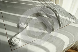 Folded white bathrobe on the bed in hotel room.