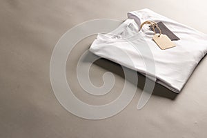 Folded white t shirt with tags with copy space on brown background