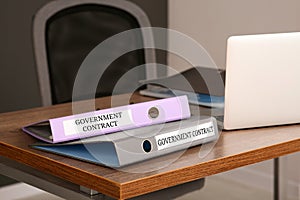 Folders with Government Contract labels on desk in office