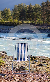 Folding chairs on the bank of a mountain river on a nice, warm day.