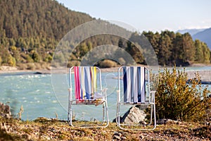 Folding chairs on the bank of a mountain river on a nice, warm day.