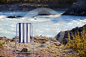 Folding chairs on the bank of a mountain river on a nice, warm day.