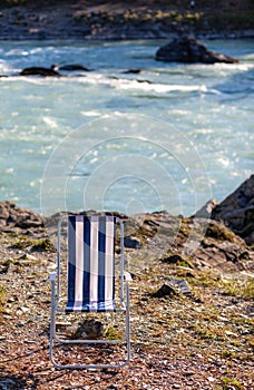 Folding chairs on the bank of a mountain river on a nice, warm day.