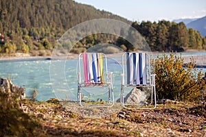 Folding chairs on the bank of a mountain river on a nice, warm day.