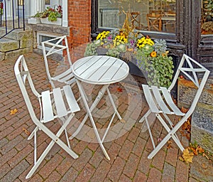 folding chairs and round table outdoor seating, brick sidewalk in Fall at restaurant