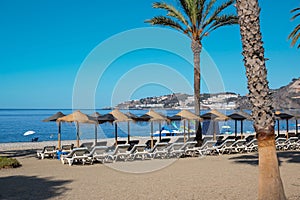 Folding chairs and umbrellas before the seascape in Almunecar beach on a sunny day