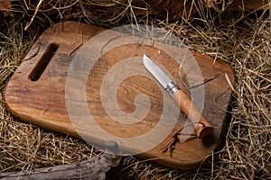 Folding French knife with wooden handle. Knife on a cutting board. Copy space.