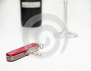 Folding knife with wine opener, glass and wine bottle on a white background