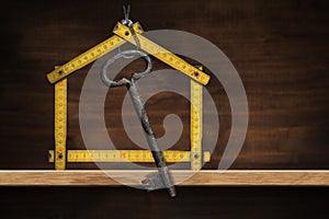 Folding Ruler House Shaped With an Old Key on a Wooden Shelf