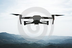 Folding small drone is flying over the mountains.