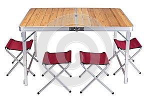 Folding table for camping on a white background, stands in the unfolded state, next are folding chairs, four red chairs