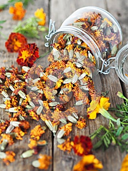 Folk medicine. Dried red flowers of marigold-marigolds on a wooden background in a glass jar for storage.The benefits of medicinal