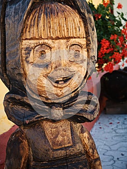 Folk wooden carved statue of a girl in front of a house in Vlkolinec, Slovakia