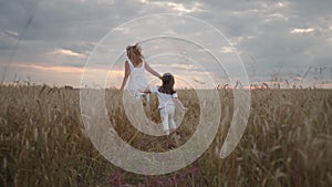 follow :Daughter and mother dream together run in the wheat field at sunset. happy family people in the wheat field