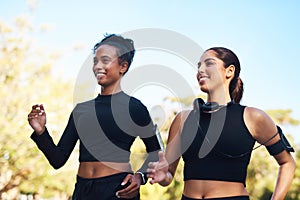 We follow each others pace. two attractive young women running next to each other in the park during the day.