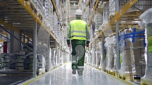 Follow footage of employee man warehouse worker engineer in hard hat working. architect walking