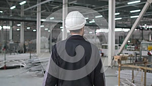 Follow footage of professional male engineer man in hard hat walking in modern industrial manufacturing