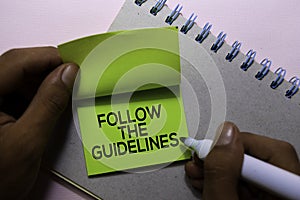 Follow The Guidelines text on sticky notes isolated on office desk