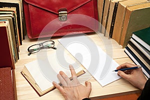 Follow the law. Professional lawyer sitting at the table and signing papers. On a wooden table books, documents, glasses, red brie