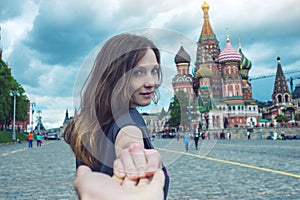 Follow me, Attractive brunette girl holding the hand leads to the red square in Moscow. Russia.