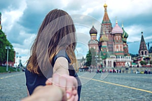 Follow me, Attractive brunette girl holding the hand leads to the red square in Moscow. Russia.