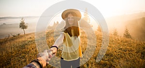 Follow me concept. Couple in love holding hands. Woman in yellow shirt and straw hat holding man by hand going to autumn