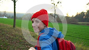 Follow me - happy young woman in red hat pulling guy`s hand. Hand in hand walking among the fields in the countryside