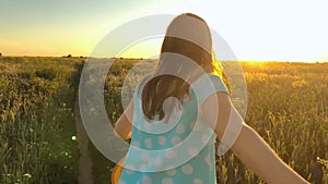 Follow me - happy young woman in yellow hat pulling guy`s hand. Hand in hand walking throw a field of green wheat at