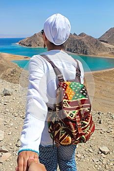 Follow me to the sea, a woman with a colorful backbag heading to the sea with mountains