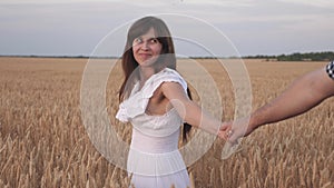 Follow me, a young happy couple running along the golden wheat field. hand in hand. lovers man and woman travel in the