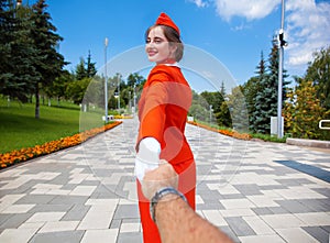 Follow Me, Young stewardess dressed in official red uniform of Airlines, Summer park outdoors