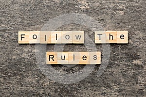 Follow The Rules word written on wood block. Follow The Rules text on table, concept