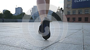 Follow to female legs in high heels shoes walking in the urban street. Feet of young business woman in high-heeled