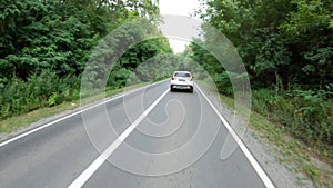 Follow to white car riding through forest road. SUV driving at beautiful countryside wood route on summer. Holidays