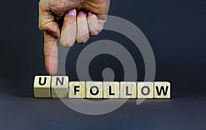 Follow or unfollow symbol. Businessman turns wooden cubes and changes words follow to unfollow. Beautiful grey background, copy