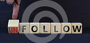 Follow or unfollow symbol. Turned wooden cubes and changed concept words Follow to Unfollow. Beautiful grey table grey background