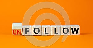 Follow or unfollow symbol. Turned wooden cubes and changed concept words Follow to Unfollow. Beautiful orange table orange