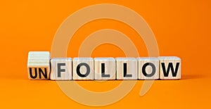 Follow or unfollow symbol. Turned wooden cubes and changed concept words Follow to Unfollow. Beautiful orange table orange