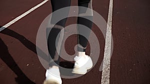 Follow-up shot of young slim fitness runner legs. girl running on stadium track