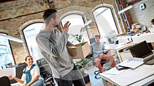 Follow your dreams, quit your job. Handsome man in casual wear holding box with personal things and saying good bye to