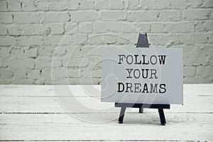 Follow your Dreams text on white brick wall and wooden background