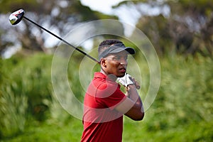 Follow through on your goals. a handsome young man taking a golf swing.