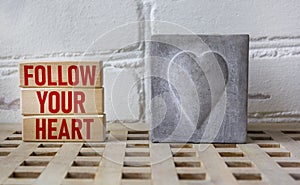 Follow your heart word written on a wooden block with a vintage heart candle