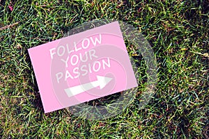 Follow your passion quote written on pink paper on green grass background. Persistence, passion and success concept