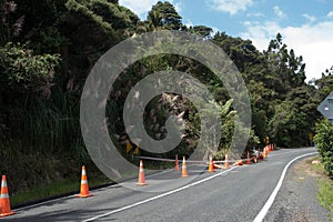 Following cyclone Gabrielle a land slip has occurred blocking one half of a road.Orange safety cones are in place