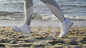 Following shot of the legs of a runner exercising on the beach. Feet of a jogger