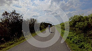 Following Woman Riding Bicycle On Narrow Path