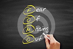 FOMO - Fear Of Missing Out, acronym concept on blackboard